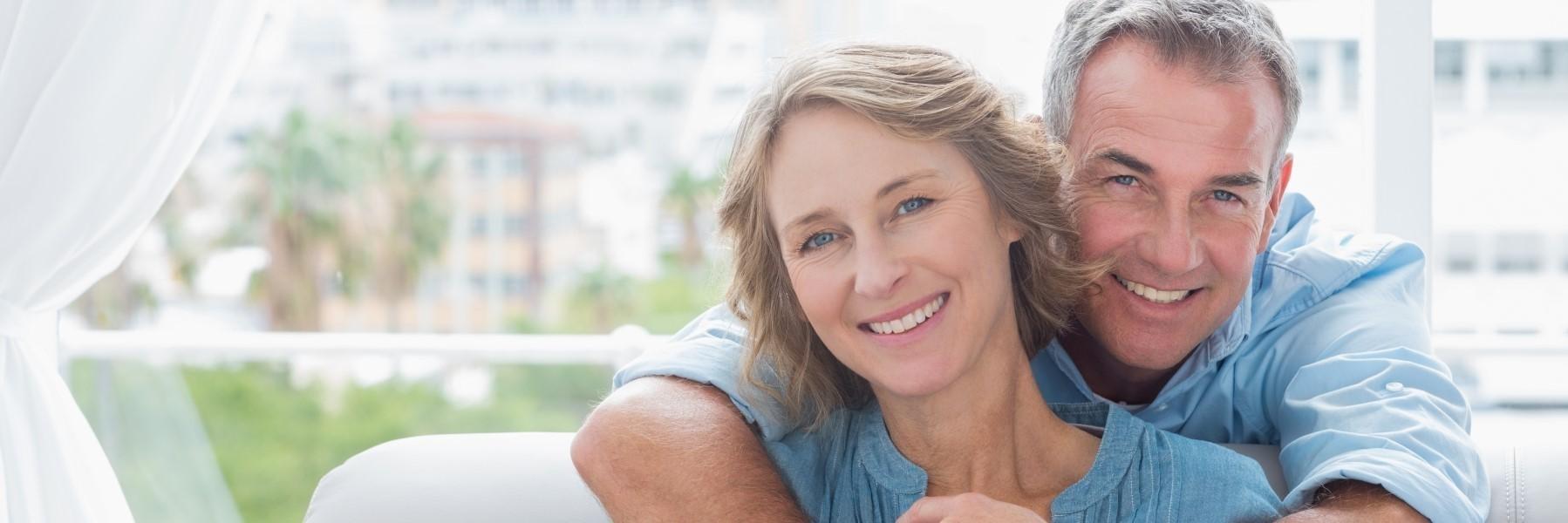 Older couple hugging & smiling l Cosmetic dentist Family Dentistry of Royal Oak