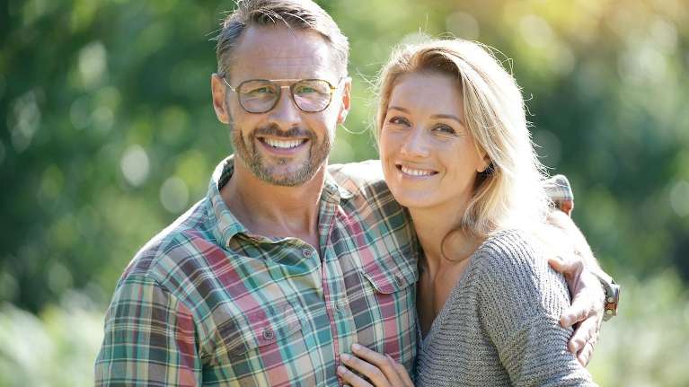 Couple with a beautiful smile after getting dental implants in Royal Oak, MI