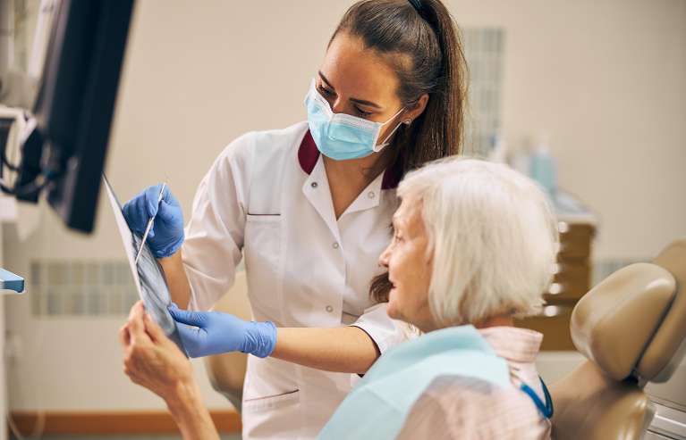 A Family Dentist attending to an elderly lady in Royal Oak, MI