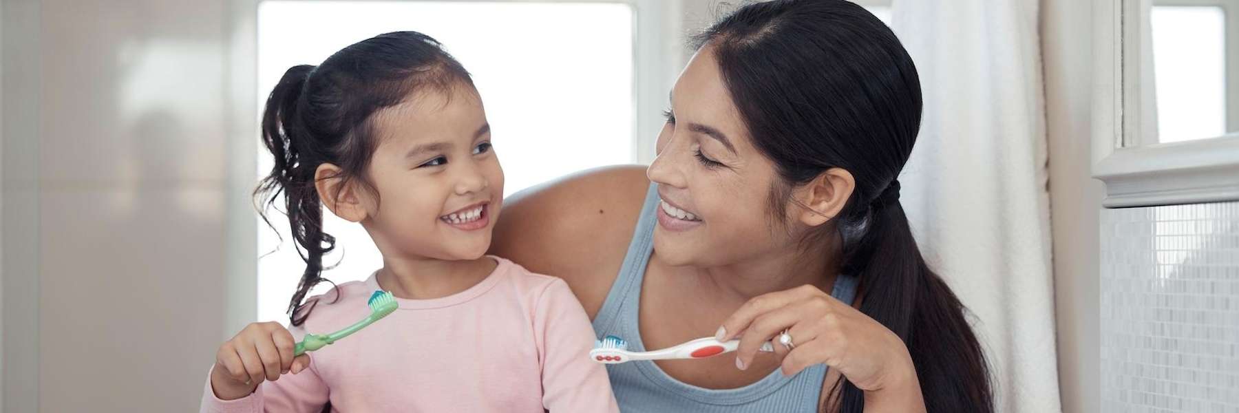 A mother and daughter brushing their teeth in Royal Oak, MI